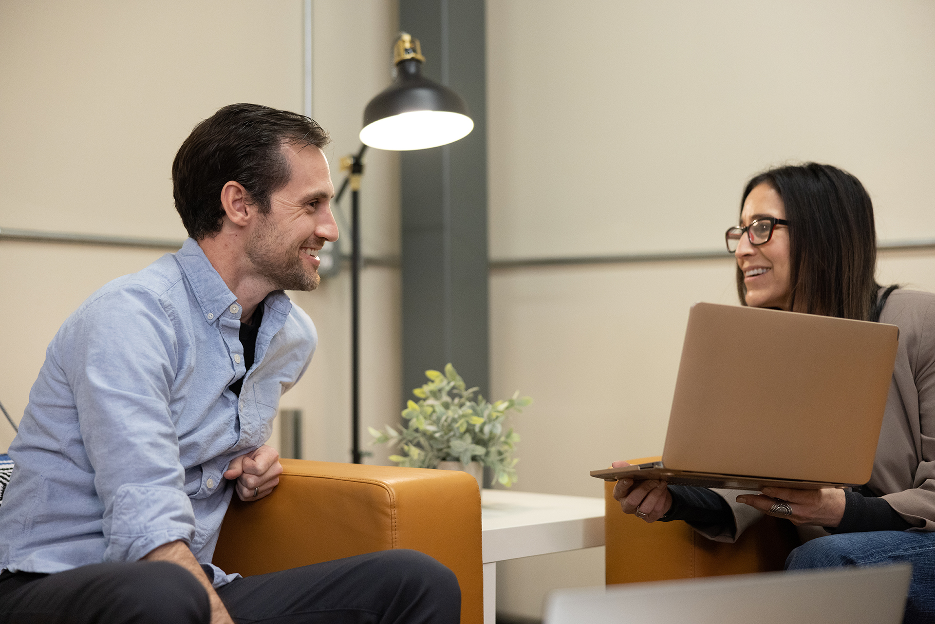 A man and woman sitting in an office with a laptop.