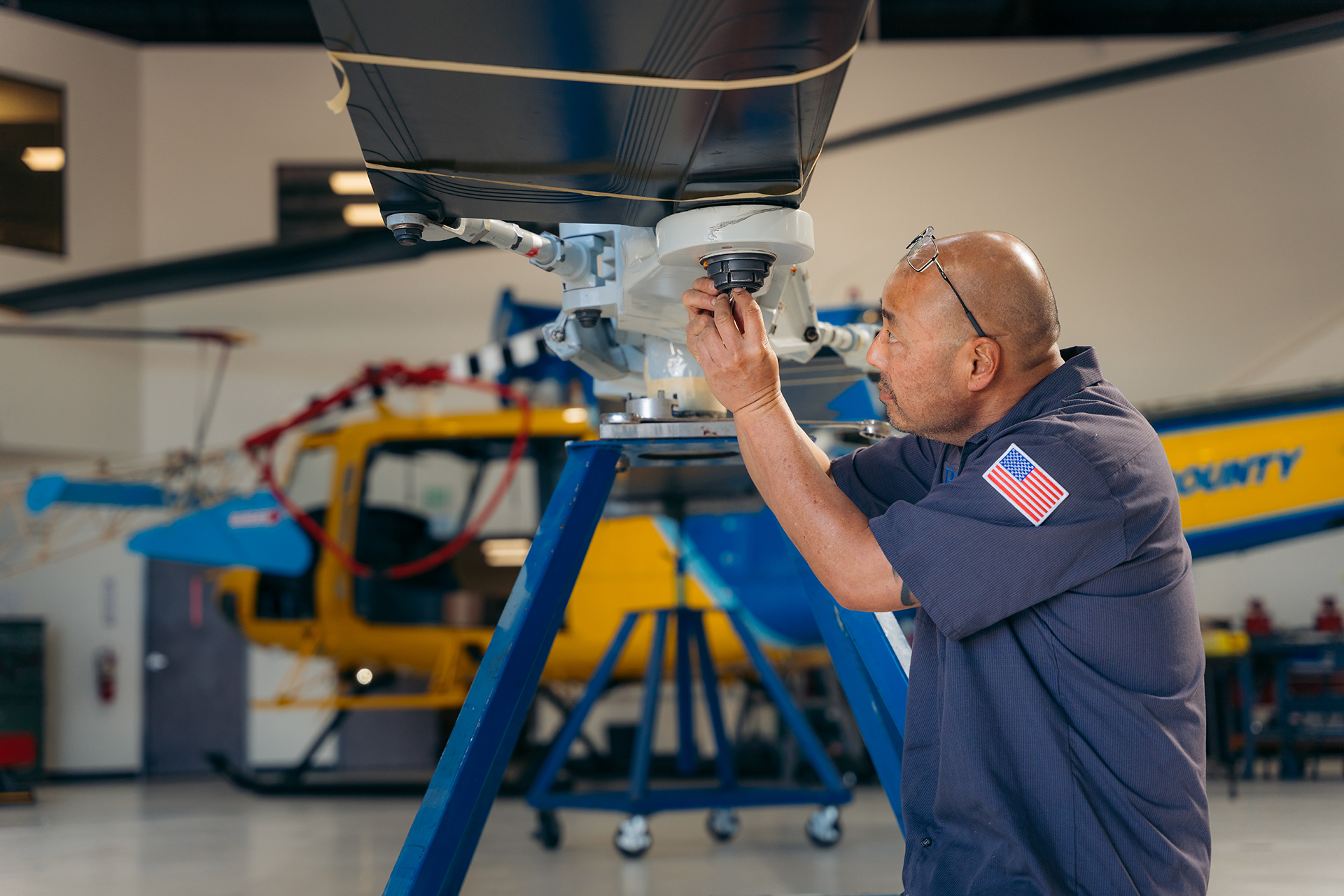 A man working on a helicopter in a hangar.