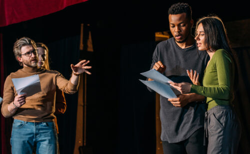 theater director, multicultural actors and actress rehearsing on stage